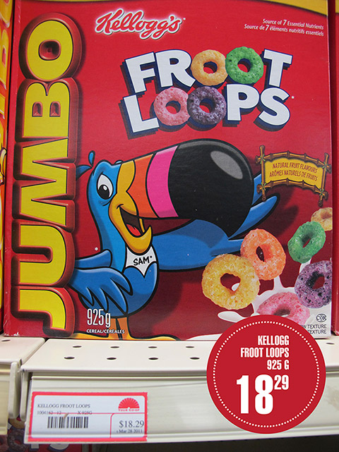 A 925 gram box of Kellogg's Froot Loops brand cereal rests on a display. A label specifies its selling price of $18.29.